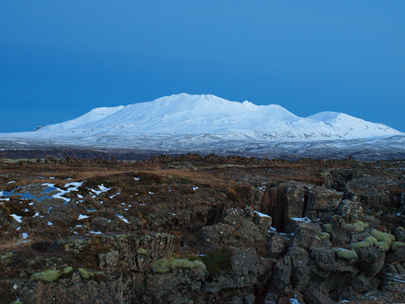 barren landscape with snow covered mountain in the background